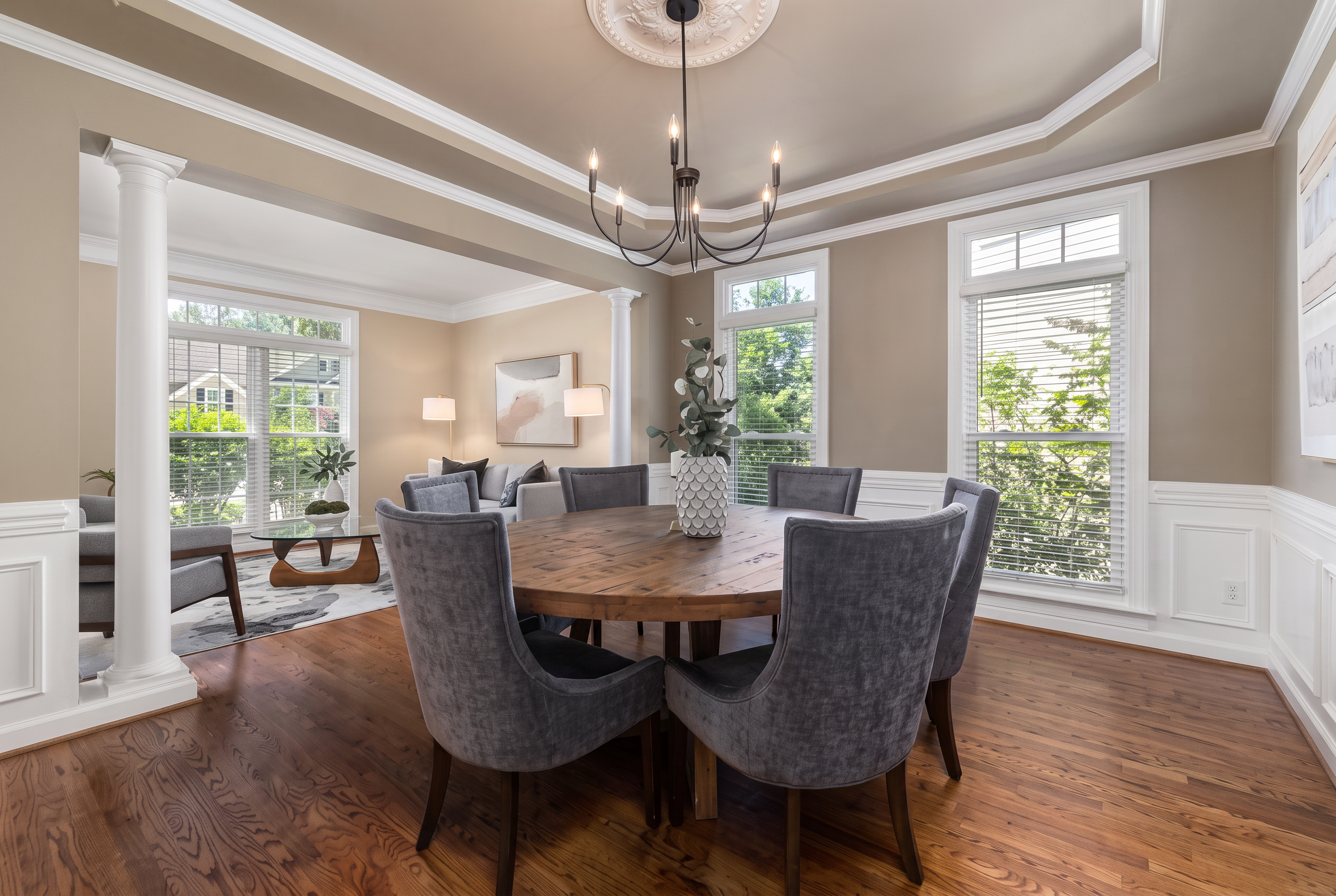 Tray-ceiling dining room with layered white crown molding, wainscoting, and hardwood floors in an Ozark, MO home